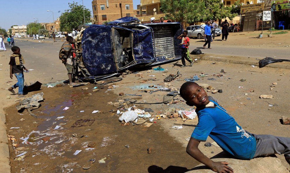 Varios niños juegan cerca de un coche de la policía volcado y dañado por los familiares de un manifestante que murió de una herida de bala durante las protestas antigubernamentales en Jartum, Sudán.-REUTERS / Mohamed Nureldin Abdallah