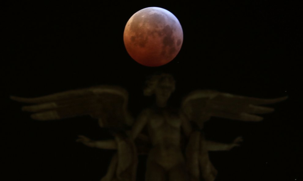 La luna durante el eclipse sobre la Victoria Alada, la estatua que corona el edificio Metrópoli en Madrid, España. REUTERS/Sergio Perez