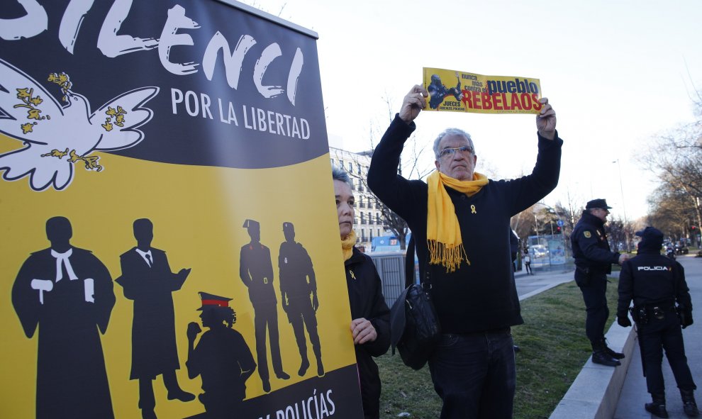 Una persona con lazo y bufanda amarilla y con un cartel que induce a la justicia a colabora con el independentismo en una concentración frente al Tribunal Supremo