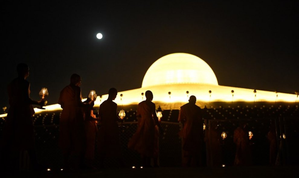 Monjes budistas llevan velas encendidas a las oraciones en el templo de Wat Phra Dhammakaya, cerca de Bangkok | AFP/ Lillian Suwanrumpha