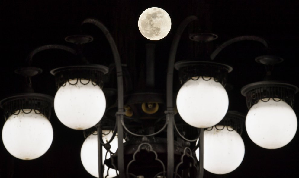 Imagen de la superluna frente a las luces de la calle de la Piazza del Duomo en el centro de Milán | AFP/ Andreas Solaro