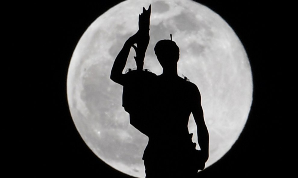 Estatua en la parte superior de la catedral del Duomo de Milán mientras se eleva la luna de nieve | AFP/ Andreas Solaro