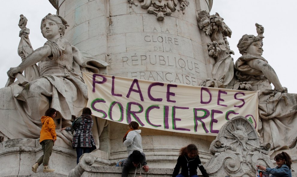 Un grupo de mujeres cuelga un cartel en la estatua de la Plaza de la República en la que se puede leer: "Plaza de las brujas".  REUTERS/Philippe Wojazer