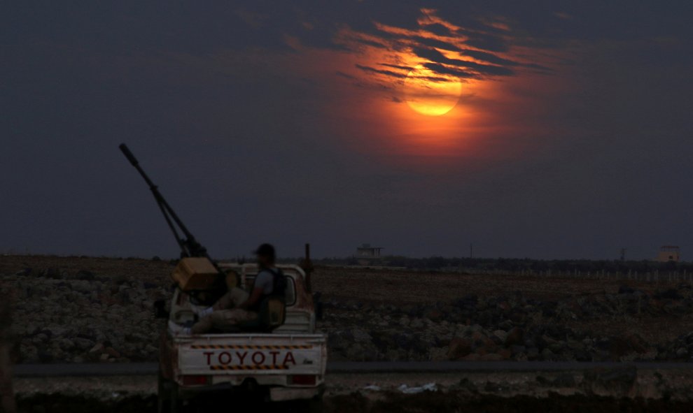 Combatientes del Ejército Libre Sirio en la ciudad controlada por los rebeldes de Dael con la superluna apareciendo entre las nubes. - REUTERS/Alaa Al-Faqir
