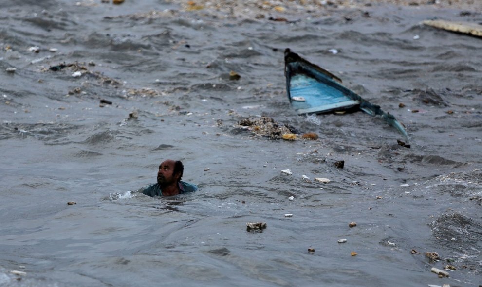 Un pescador nada a la orilla después de que su bote se volcó debido a las fuertes olas que se avecinaban antes de la llegada del ciclón Vayu en Veraval, India | Reuters