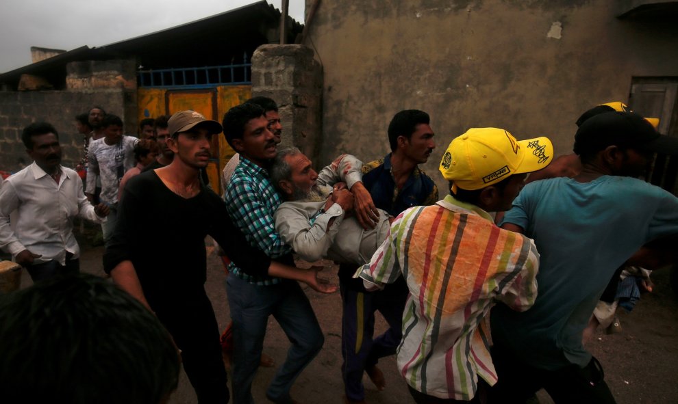 Un grupo de pescadores auxilian a un compañero que resultó herido después de que su bote volcara debido a las fuertes olas a consecuencia del 'ciclón Vayu' | Reuters