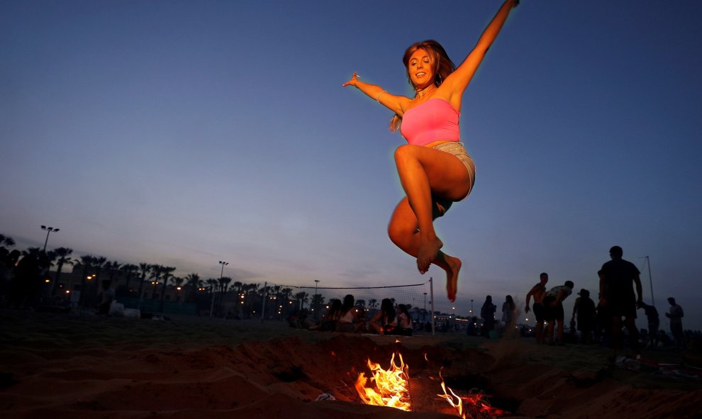 Una mujer salta sobre una hoguera para celebrar la noche de San Juan en la playa La Malvarrosa en València | EFE