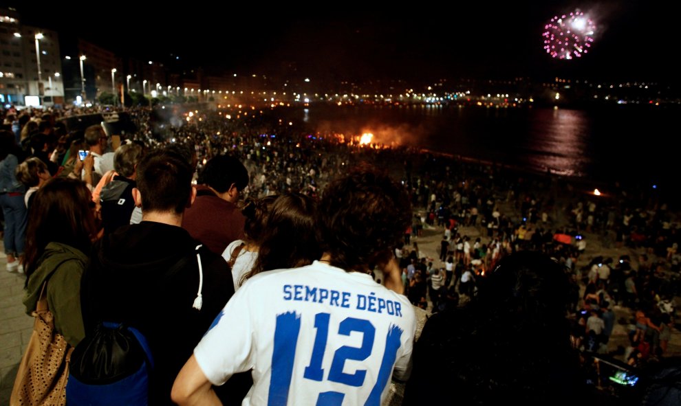 Un grupo de jóvenes disfruta de la noche de San Juan en torno a las hogueras que iluminaron las playas de A Coruña | EFE