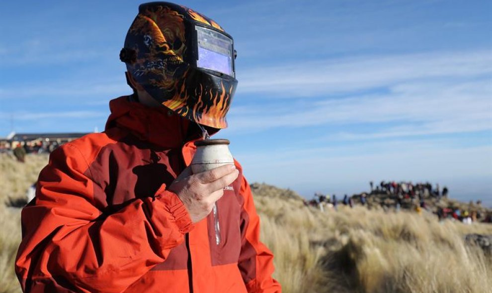 Un hombre observa el eclipse solar total con una máscara de soldar mientras toma mate, este martes, en la ciudad de Merlo, San Luis (Argentina). EFE