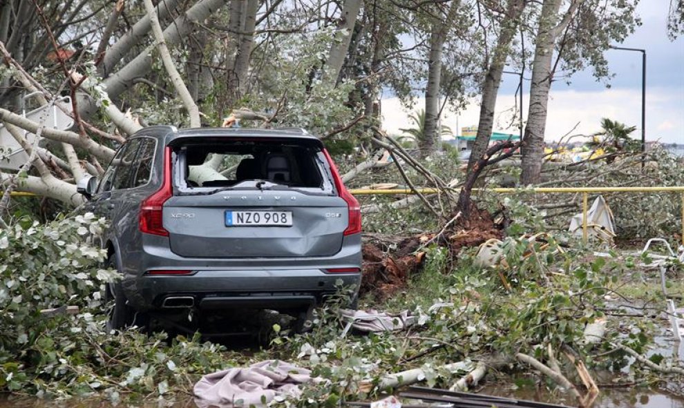 Un coche enterrado en árboles caídos. EFE / VERVERIDIS VASSILIS