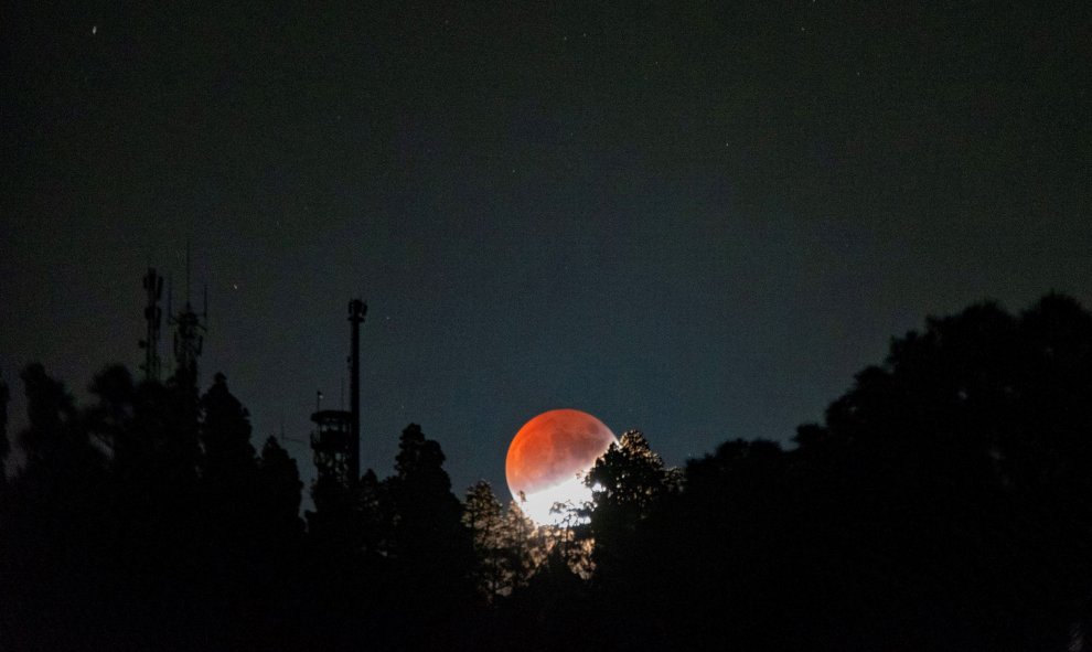 17/07/2019.- La luna eclipsada asoma esta noche por la montaña de Las Tricias, en el municipio de Garafía, al norte de la isla de La Palma. EFE/MIGUEL CALERO