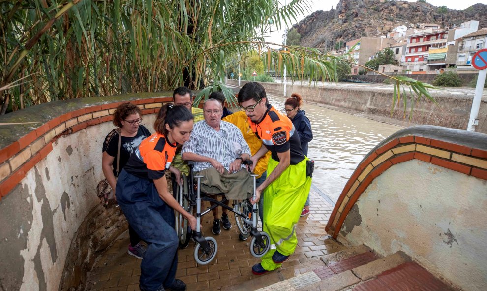 12/09/2019.- Voluntarios de protección civil trasladan a un hombre en silla de ruedas tras las intensas lluvias esta tarde en el barrio de Runes, Blanca, (Murcia), EFE/Marcial Guillén