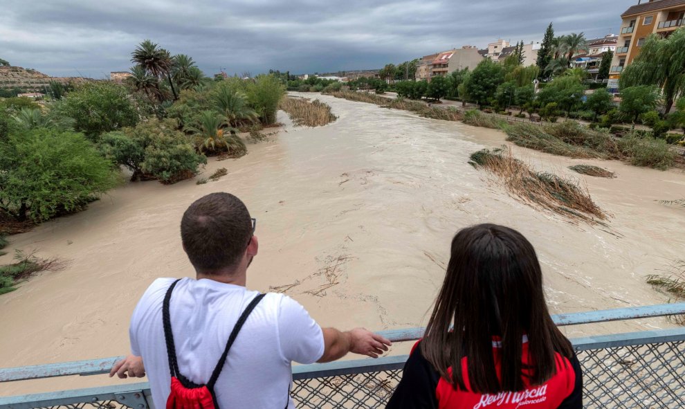 Dos chicos observan la crecida del río Segura tras desbordarse por las dos márgenes a su paso por Archena, Murcia, tras las fuertes lluvias caídas en las últimas horas. EFE/Marcial Guillén