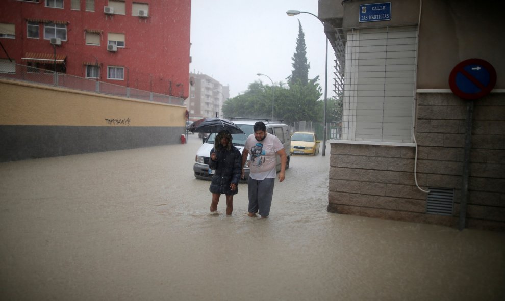 La gente cruza una calle inundada cerca del desbordante río Segura cuando las lluvias torrenciales azotan Orihuela, cerca de Murcia. REUTERS / Jon Nazca