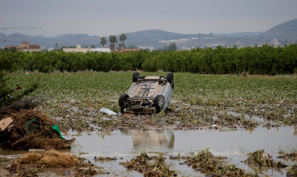 Un automóvil volcado en mitad de un campo tras ser arrastrado por las lluvias torrenciales de la gota fría en Orihuela.- REUTERS /  JON NAZCA