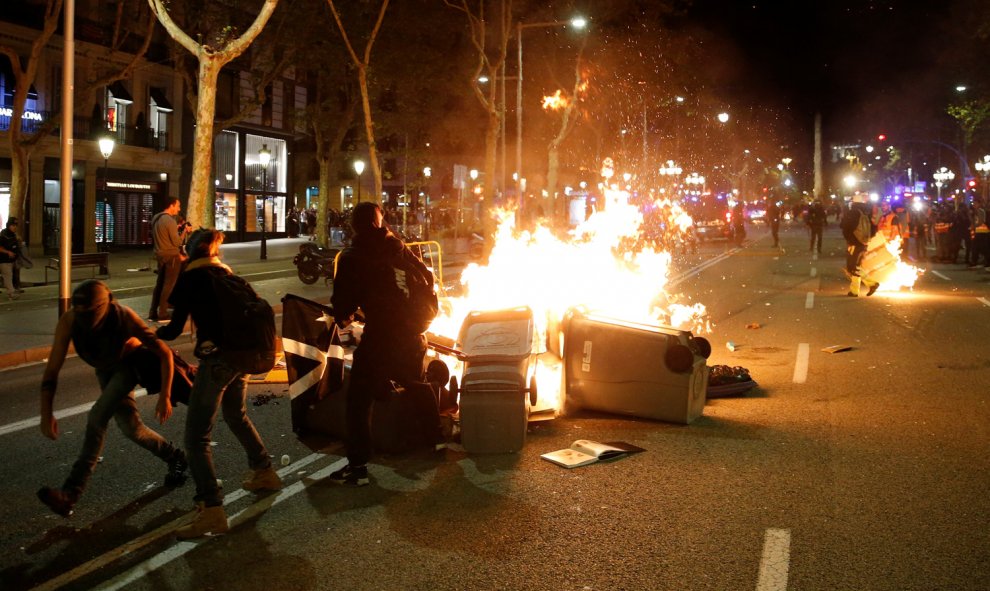 Contenedores ardiendo entre varios manifestantes y los Mossos durante las protestas en el centro de Barcelona. /REUTERS