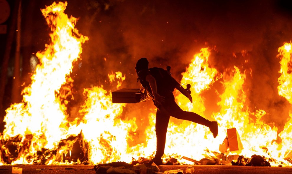 15/10/2019.- Un manifestante echa al fuego un cartón junto a la Delegación del Gobierno en Barcelona durante los incidentes producidos al finalizar la movilización convocada por los CDR, hoy martes en la segunda jornada de protestas contra la sentencia c