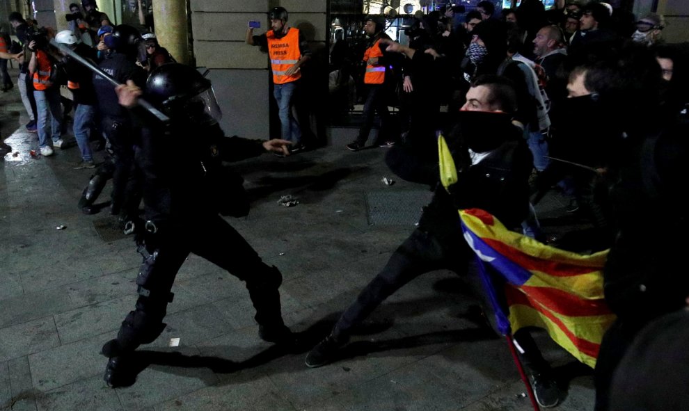 Un antidisturbios de los Mossos d/Equadra golpea con la porra a los manifestantes independentistas en Barcelona.- REUTERS/ALBERT GEA