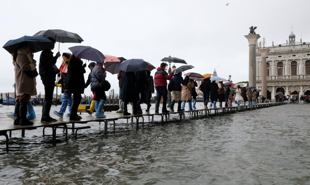 Decenas de transeúntes hacen cola en una pasarela durante este martes durante la temporada de marea alta. REUTERS