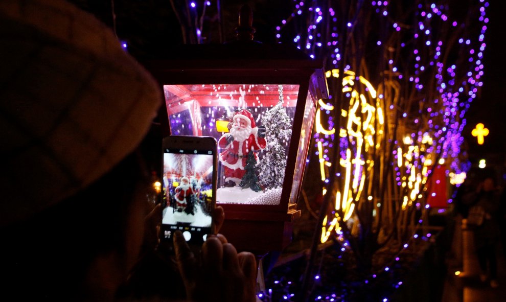 Una mujer toma fotos de una decoración de Santa Claus con su teléfono en la Catedral Xishiku, una iglesia católica sancionada por el gobierno, en la víspera de Navidad en Beijing, China, 24 de diciembre de 2019. REUTERS / Florence Lo