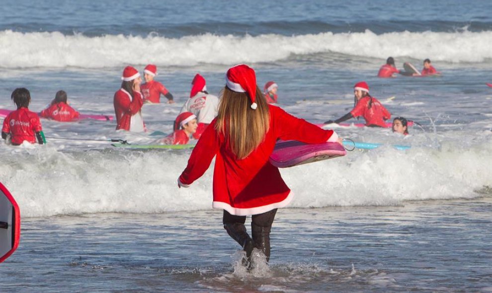 Un año más los Papá Noeles surferos se han dado cita en la playa de Patos en Nigrán para cabalgar las olas en un día primaveral, que hacía tiempo que no se veía en Galicia . EFE / Salvador Sas