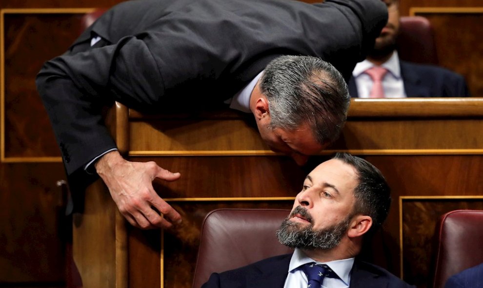 El presidente de Vox, Santiago Abascal, escucha a su compañero de grupo, Javier Ortega Smith (i), en el Congreso de los Diputados en la primera jornada de la sesión de investidura de Pedro Sánchez como presidente del Gobierno. EFE/Juan Carlos Hidalgo