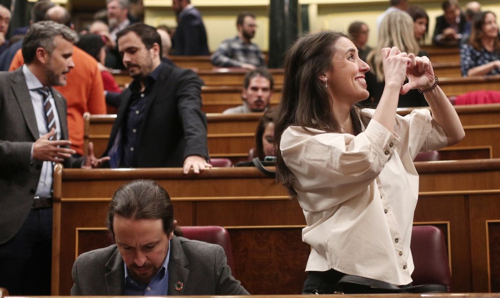 La portavoz de Unidas Podemos en el Congreso, Irene Montero, hace el signo de un corazón con las manos hacia alguien en la tribuna de invitados, junto al secretario general de Podemos, Pablo Iglesias, momentos antes de empezar la segunda sesión de votació