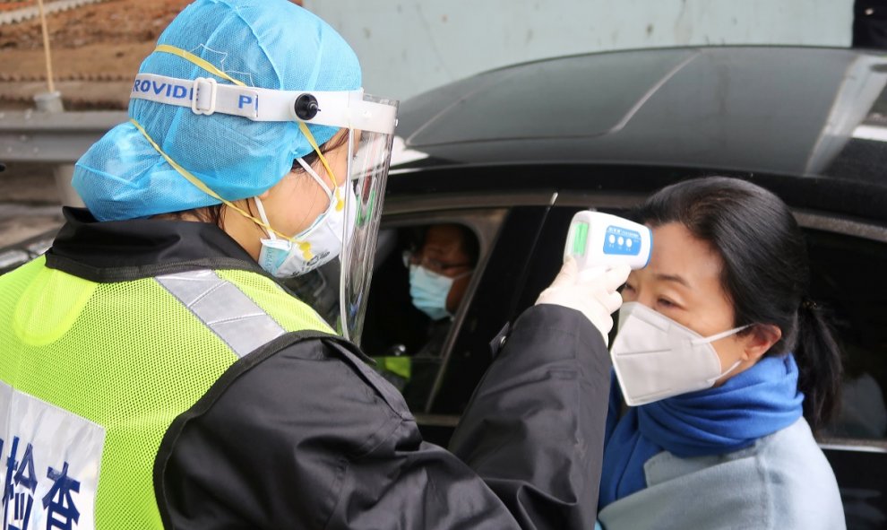 Un oficial de seguridad toma la temperatura a una pasajera tras el brote del coronavirus. REUTERS