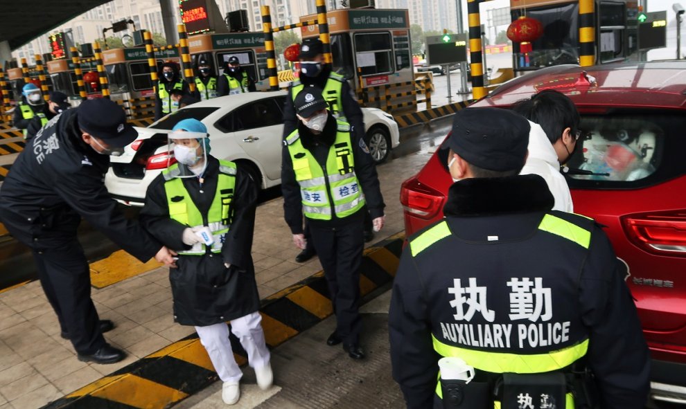 Oficiales de policía revisan el maletero de un coche en una ciudad fronteriza de Wuhan. REUTERS