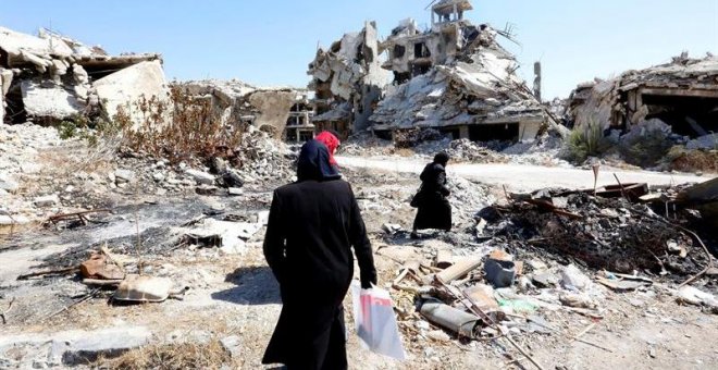 Mujeres sirias caminan entre las ruinas de la ciudad Homs, Siria. EFE/Youssef Badawi