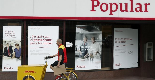 Un repartidor pasa ante una oficina del Banco Popular en Barcelona. EFE/Andreu Dalmau