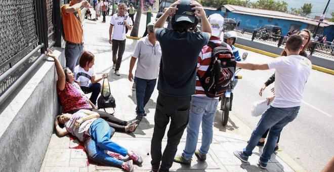 os mujeres yacen en el suelo durante un enfrentamiento entre un grupo de personas adeptas al oficialismo y personas opositoras al gobierno nacional durante la consulta popular hoy, domingo 16 de julio de 2017, en el oeste de Caracas (Venezuela). Dos perso