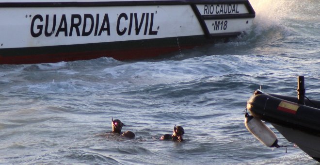 Miembros del Grupo Especial de Actividades Subacuáticas (GEAS) de la Guardia Civil sacan del agua el cuerpo de un inmigrante subsahariano que ha fallecido ahogado tras ser abandonado, junto a otros once inmigrantes, por seis motos de agua que los transpor