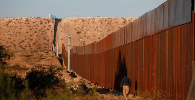Un hombre pasa por una sección del muro que separa EEUU de México, cerca de Ciudad Juarez. - REUTERS