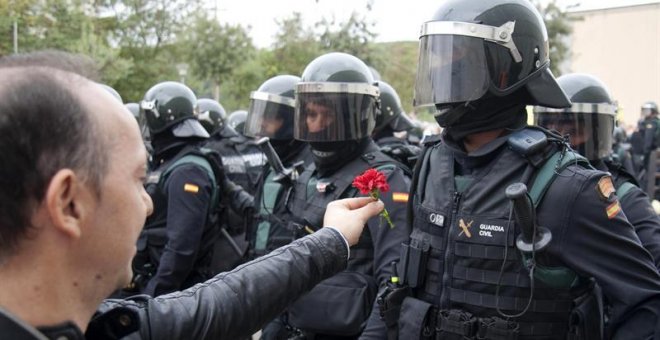 Un hombre ofrece un clavel a un agente de la Guardia Civil en el centro de votación de Sant Julià de Ramis (Girona) donde inicialmente tenía previsto votar el presidente de la Generalitat, Carles Puigdemont, en el referéndum independentista del 1-O./ EFE