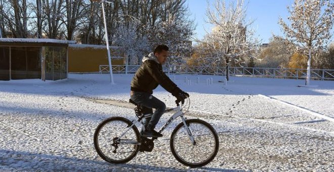 Un hombre se desplaza en bicicleta en medio del temporal de frío y nieve que afecta a León. / EFE