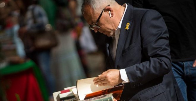 Un hombre con un lazo amarillo en la solapa de su chaqueta hojea un libro en una de las paradas de las Ramblas de Barcelona. / EFE