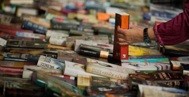 Un hombre compra un libro en un puesto de libros de las Ramblas de Barcelona durante la diada de Sant Jordi. (ENRIC FONTCUBERTA | EFE)