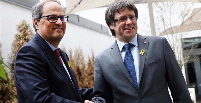 El recién elegido presidente de la Generalitat de Catalunya, Quim Torra (izq), estrecha la mano a su predecesor, el expresidente regional catalán Carles Puigdemont, en Berlín. (OMER MESSINGER | EFE)