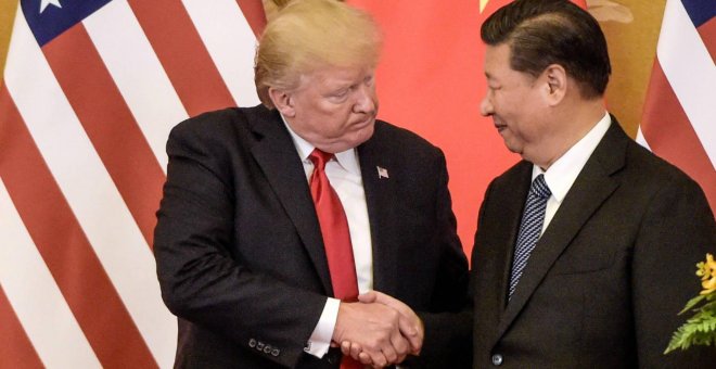 Donald Trump, a la izquierda, estrechando la mano del líder chino, Xi Jinping - FRED DUFOUR/AFP