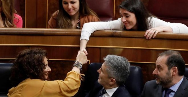 La ministra de Hacienda, María Jesús Montero (i - 1ªfila), estrecha la mano con la portavoz de Podemos en el Congreso, Irene Montero (d - 2ª fila), durante su intervención en la segunda jornada del debate de las enmiendas a la totalidad del proyecto de Pr