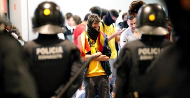 Agentes de los Mossos d'Esquadra controlan a los simpatizantes independentistas que han conseguido entrar en el T1 del Aeropuerto de El Prat tras el anuncio de la plataforma Tsunami Democràtic que ha llamado a paralizar la actividad del aeropuerto, en pr