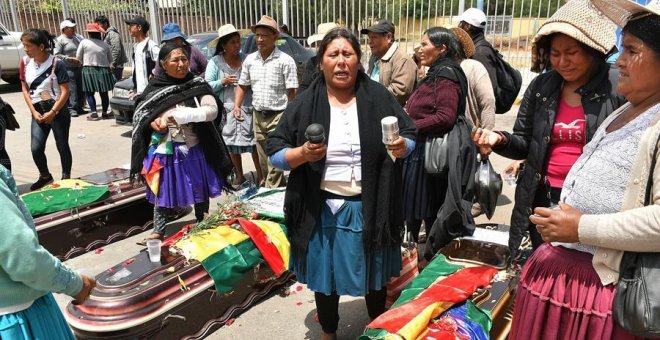 16/11/2019.- Un grupo de mujeres realiza una ceremonia ante los féretros de varios de los fallecidos tras los disturbios de ayer con las fuerzas del orden, frente al Instituto de Investigaciones Forenses este sábado, en Cochabamba (Bolivia). El número de