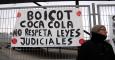 Un empleado de Coca-Cola junto a una pancarta que pide que la empresa acate la sentencia judicial. -JAIRO VARGAS