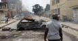 Un hombre junto a un coche quemado en Kinshasa a modo de barricada. - REUTERS