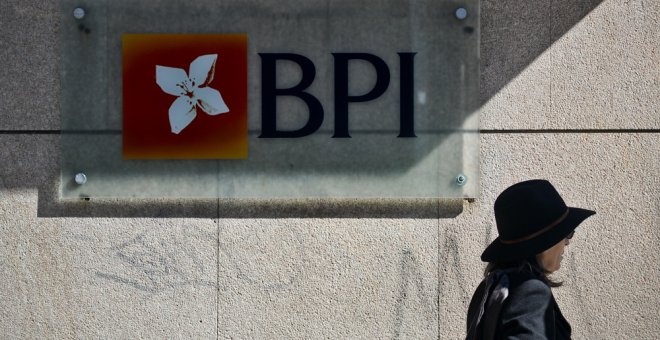 Una mujer pasa junto a una oficina del banco BPI en Lisboa.  AFP / Patricia de Melo Moreira