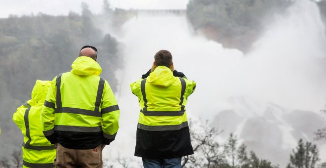 California Department of Water Resources personnel monitor water flowing through a damaged spillway on the Oroville Dam in Oroville, California