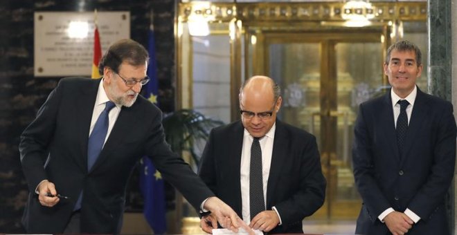 El presidente del Gobierno, Mariano Rajoy (i), durante firma con el secretario general de CC, José Miguel Barragán (c), del acuerdo suscrito entre sus dos partidos sobre los presupuestos generales del Estado de 2017, en un acto al que asiste el jefe del