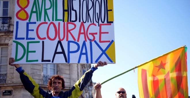 Un hombre sostiene una pancarta con la frase, en francés, "8 de abril histórico. El valor de la paz", junto a otro hombre con las banderas vasca y catalana, en baiona. REUTERS / Vincent West