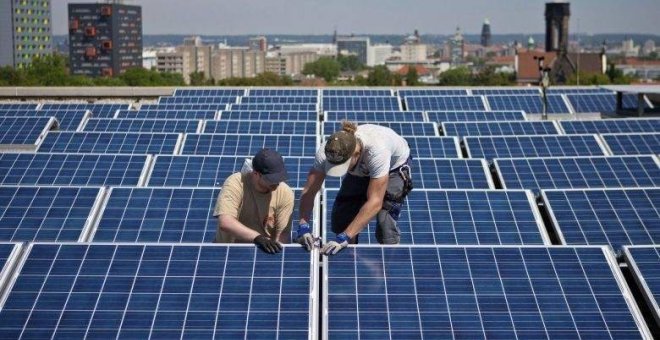 Dos operarios trabajan en las placas solares situadas en la azotea de un edificio. EFE